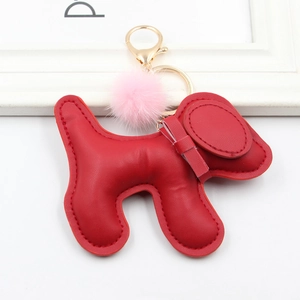 Detail of red PU leather dog keychain with pink fur pom pom and golden lobster clasp