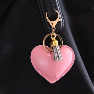 Porte-clés cœur en cuir rose avec fermoir doré et gland sur une sangle de sac noir