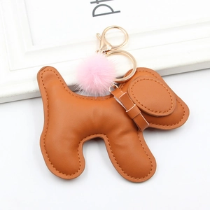 Close-up of brown PU leather puppy charm with a pink fur ball and golden metal clip