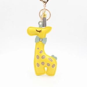 Detailed view of yellow giraffe leather keychain with grey tassel and gold metal clasp