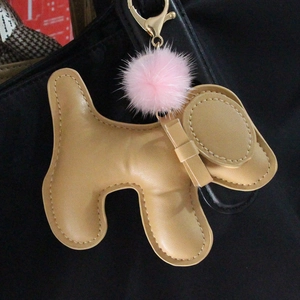 Detail of cute beige leather puppy keychain with pink fur pompom and golden lobster clasp