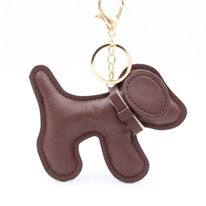 Detail of dark brown leather puppy keychain with gold ring and fine stitching