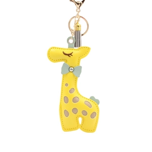 Yellow PU leather giraffe keychain with green bow and grey tassel on white background