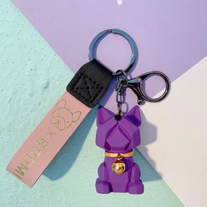 Detailed macro view of purple geometric bulldog keychain with pink leather strap and gold bell