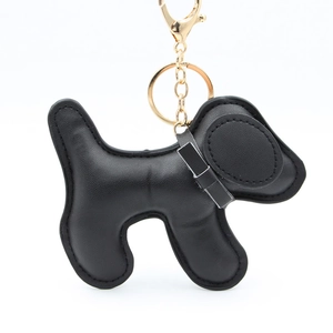 Detailed close-up of a black PU leather puppy keychain with gold metal clasp and stitching