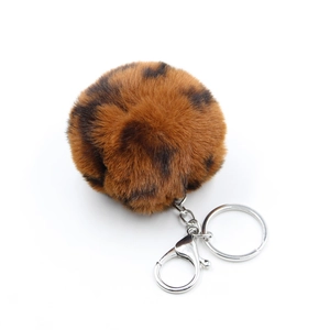 Macro shot of fluffy leopard print faux fur pompom with silver metal keychain and lobster clasp