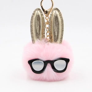Dettaglio portachiavi a sfera di peluche rosa con lunghe orecchie dorate e occhiali da sole