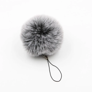 Macro detail of fluffy grey and white faux fur pompom keychain with a black lanyard