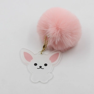 Détail d'un porte-clés pompon rose avec breloque chiot en acrylique et chaîne dorée