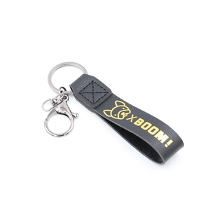 Détail du porte-clés en cuir noir avec texte XBOOM! doré et fermoir mousqueton