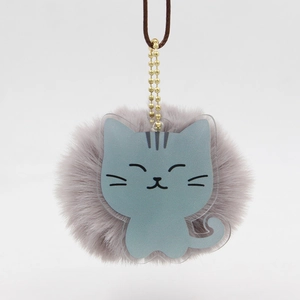 Détail d'un pendentif chaton en acrylique gris avec pompon en peluche et chaîne dorée