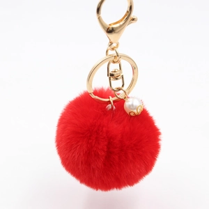 Close-up of fluffy red faux fur keychain with gold ring and elegant pearl charm detail