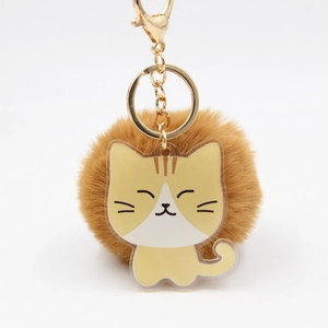 Détail d'un porte-clés chat en acrylique jaune avec pompon marron et fermoir doré