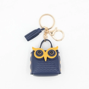 Close-up of owl-shaped blue faux leather mini coin purse with gold keychain and tassel