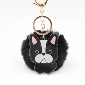 Détail d'un pompon noir en fausse fourrure avec breloque bouledogue français et métal doré