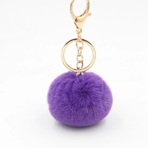 Porte-clés pompon en fourrure violette avec fermoir mousqueton doré sur fond blanc pur