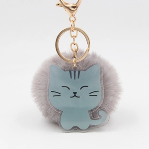 Détail d'un porte-clés pompon gris-violet avec breloque chat en acrylique bleu et crochet doré