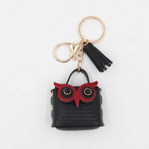Detail of owl mini pouch with black leather texture, gold tassel and keychain hook