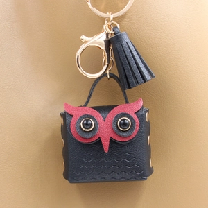 Detail of owl-shaped coin purse with black leather texture, gold hardware and tassel