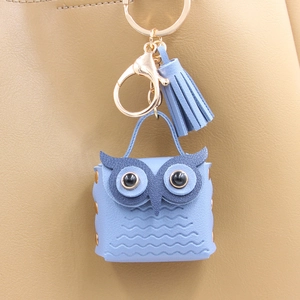 Close-up of light blue owl PU leather keychain charm with golden metal clasp and tassel