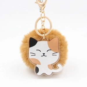 Détail d'un pompon en fausse fourrure marron et d'un porte-clés chat calicot en acrylique