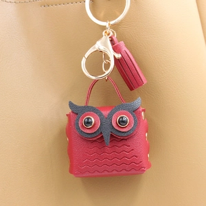 Detail of red owl leather coin purse with golden metal clasp and fringe on handbag