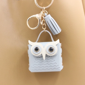 Detail of light blue owl mini pouch with golden hardware and leather tassel on bag