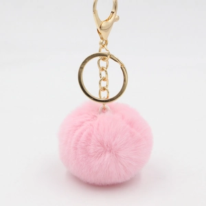 Détail d'un porte-clés pompon rose duveteux avec anneau métallique doré et fermoir homard
