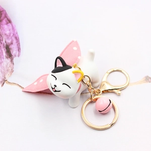 Close-up of white resin cat keychain with pink polka dot bow and small metal bell
