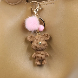 Handgefertigter brauner Häkelbär Schlüsselanhänger mit rosa Pelzquaste an Ledertasche