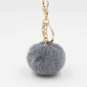 Détail d'un porte-clés pompon en fausse fourrure grise de 6cm avec fermoir doré