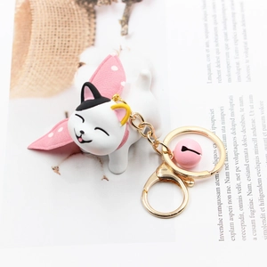Close-up of cute white resin cat keychain with pink bell and gold metal hardware