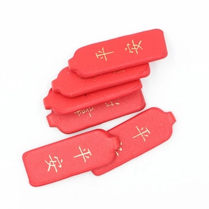 Close-up of red PU leather keychain tags with gold Pingan characters on white surface