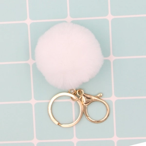 Détail d'un porte-clés pompon en fausse fourrure blanche avec fermoir doré brillant