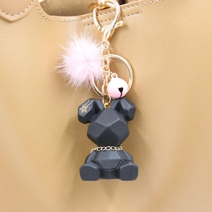 Porte-clés lapin géométrique noir avec pompon rose et clochette dorée sur un sac