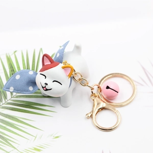 Cute resin cat keychain with a pink bell and blue bow tie on a minimalist white background