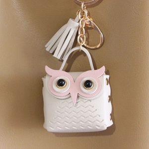 Macro shot of a white owl-shaped PU leather keychain with pink details and gold metal ring