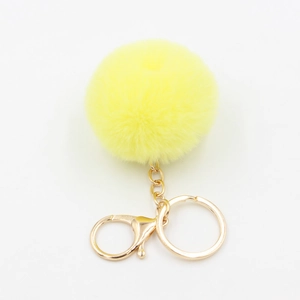 Gros plan sur un porte-clés pompon en fausse fourrure jaune vif avec fermoir doré robuste