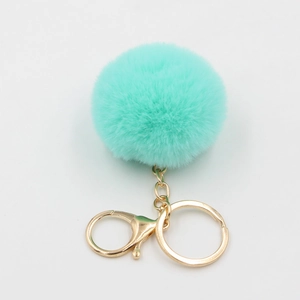 Détail d'un porte-clés pompon en fourrure vert menthe avec fermoir et anneau dorés
