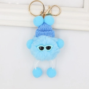 Détail d'un porte-clés en peluche bleu clair avec bonnet tricoté et lunettes bleues