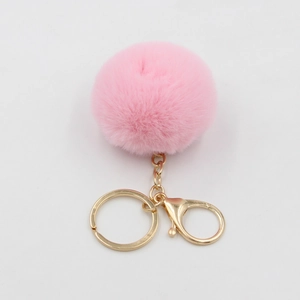 Gros plan du porte-clés pompon rose en fausse fourrure avec fermoir doré sur blanc