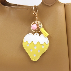 Détail du porte-clés fraise jaune avec clochette rose et pompon sur sac en cuir