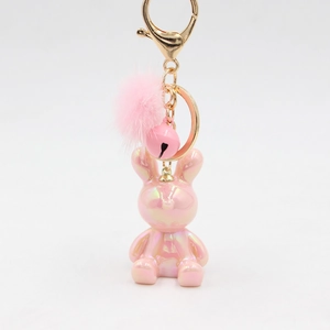 Detail of pink resin rabbit keychain with fluffy pompom, bell and golden metal hardware