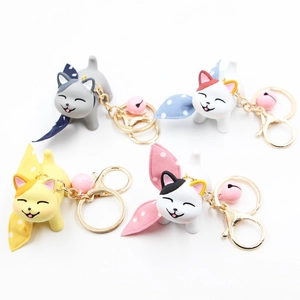 Close-up of four cute resin cat keychains with colorful bows and small golden bells