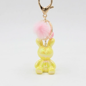 Detail of yellow pearlescent rabbit keychain with pink fur ball and golden metal clasp