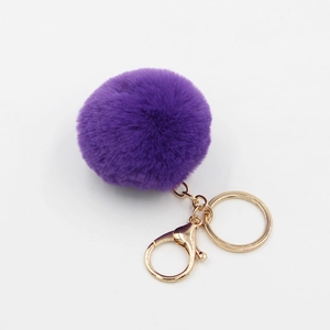 Gros plan sur le porte-clés pompon violet duveteux avec mousqueton et anneau dorés