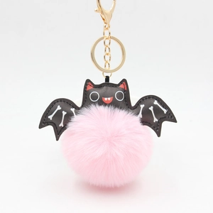 Detail of pink faux fur bat keychain with black leather wings and golden metal clasp