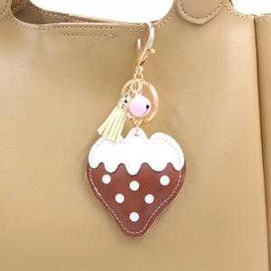 Détail d'un porte-clés fraise en cuir PU avec clochette et pompon sur un sac