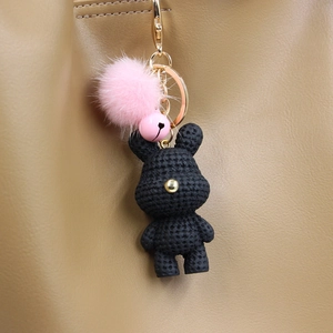 Detail eines schwarzen Strick-Hase Schlüsselanhängers mit rosa Bommel an Ledertasche