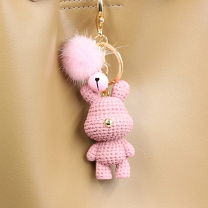 Detailansicht vom rosa Strickbär Schlüsselanhänger mit Plüschbommel an Ledertasche